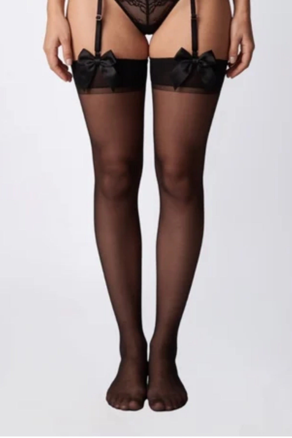 Model wearing sheer bow finish thigh-high stockings in black