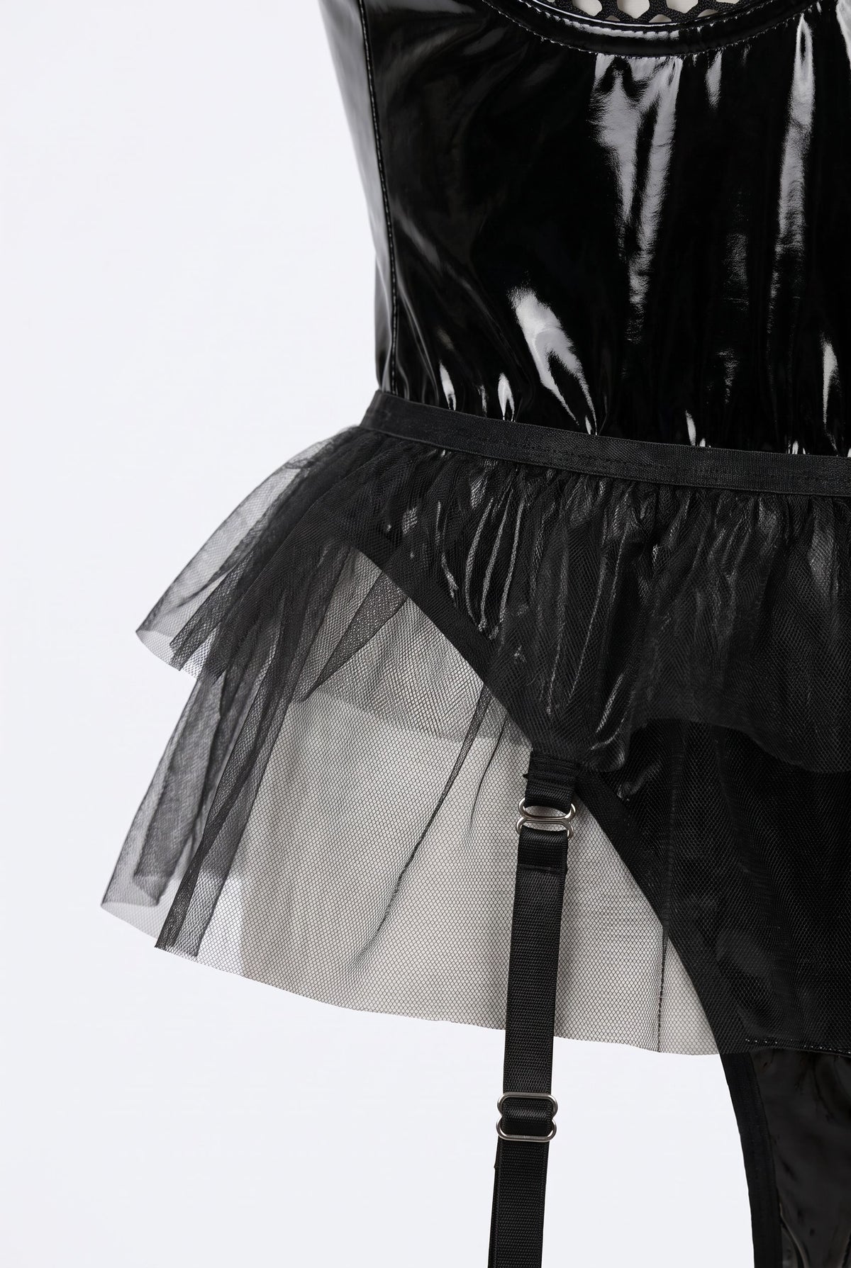 Close-up of the glossy vinyl waist, tulle peplum and garter strap clip of the midnight mesh temptation bodysuit in black