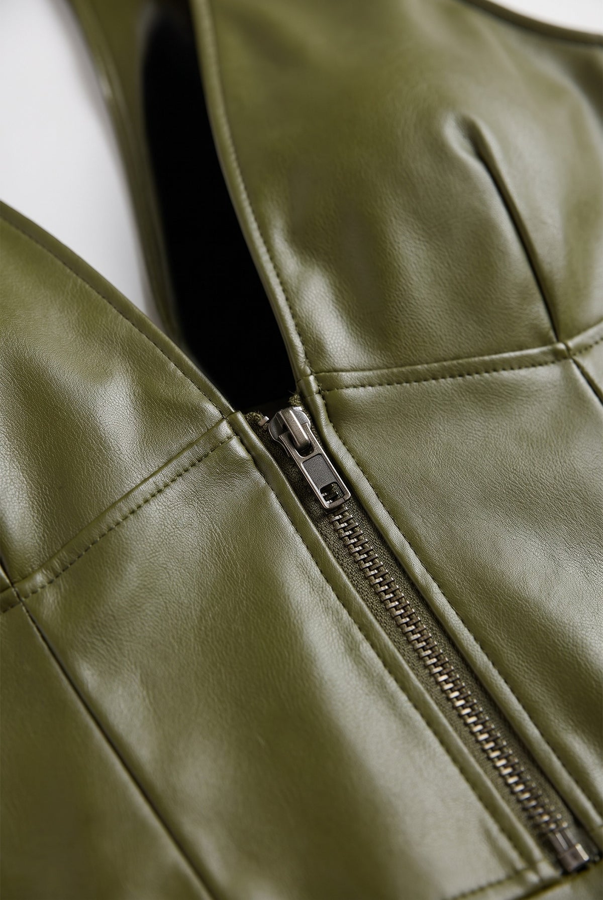 Close-up of the plunge neckline and zip of the grain finish a-line dress in green